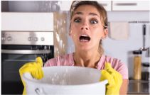 Woman Holding A Bucket While Water Droplets Leak From Ceiling